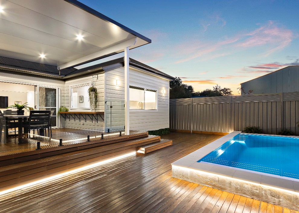 Timber deck build with in-ground pool and integrated lighting at dusk